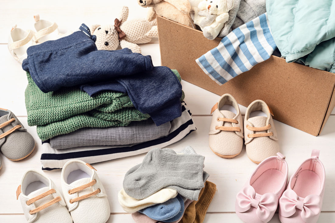 A box and pile of baby and children's clothing, with toys and shoes